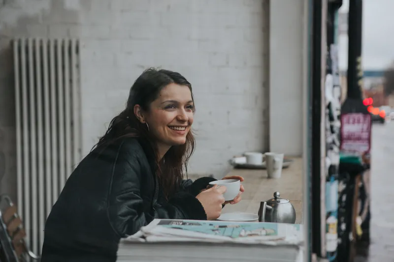 Cheerful woman holding a cup of coffee at a café counter
