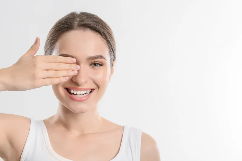 Smiling woman playfully covering one eye with her hand