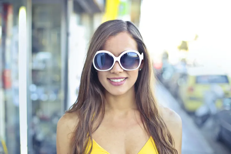 Smiling woman with white sunglasses on a sunny street