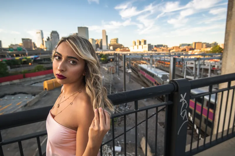 Woman on a balcony with a city skyline behind her at golden hour