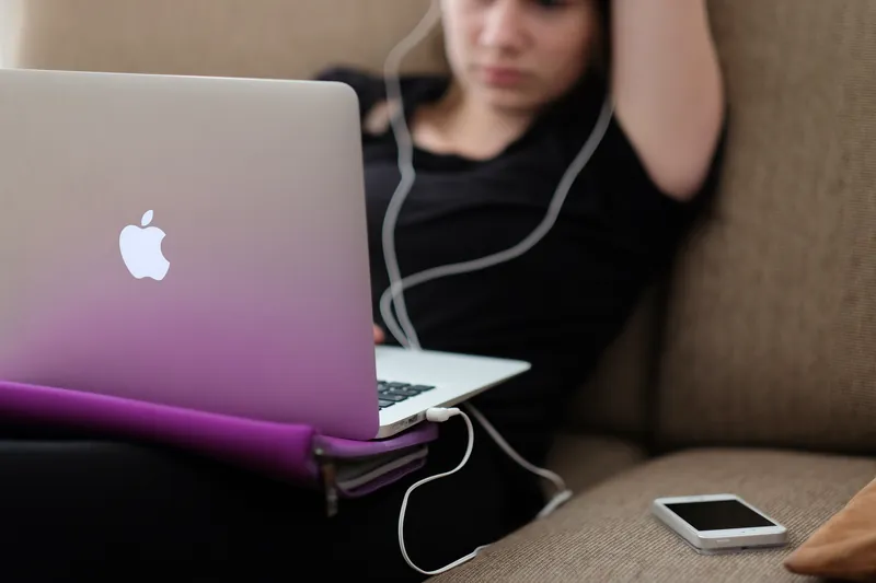 Woman relaxing on a sofa with a laptop and earphones