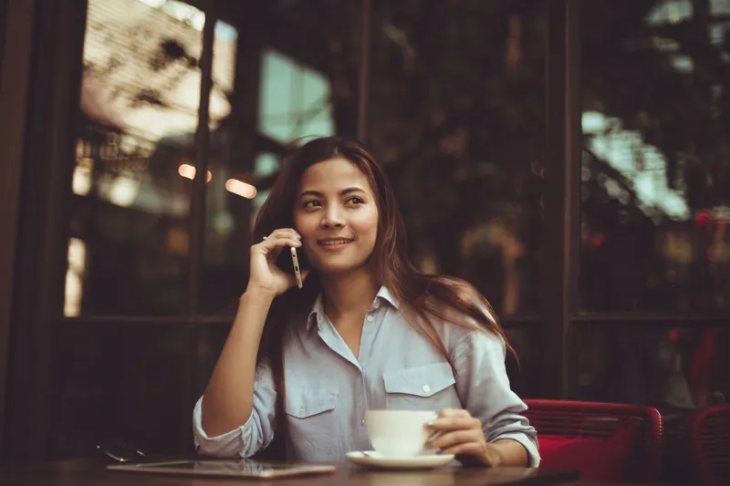 Woman smiling while talking on the phone in a cozy café