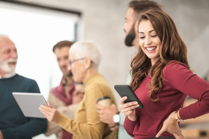 Woman in a red sweater smiling at her smartphone among friends
