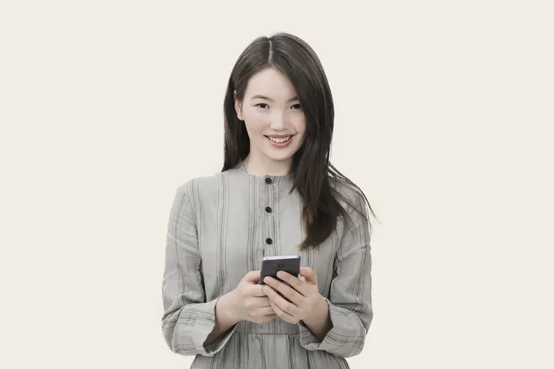 Smiling woman holding a smartphone against a light background